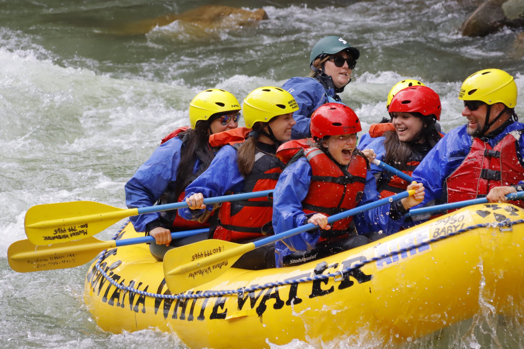 Rafters navigating white water rapids on a Montana river surrounded by canyon walls