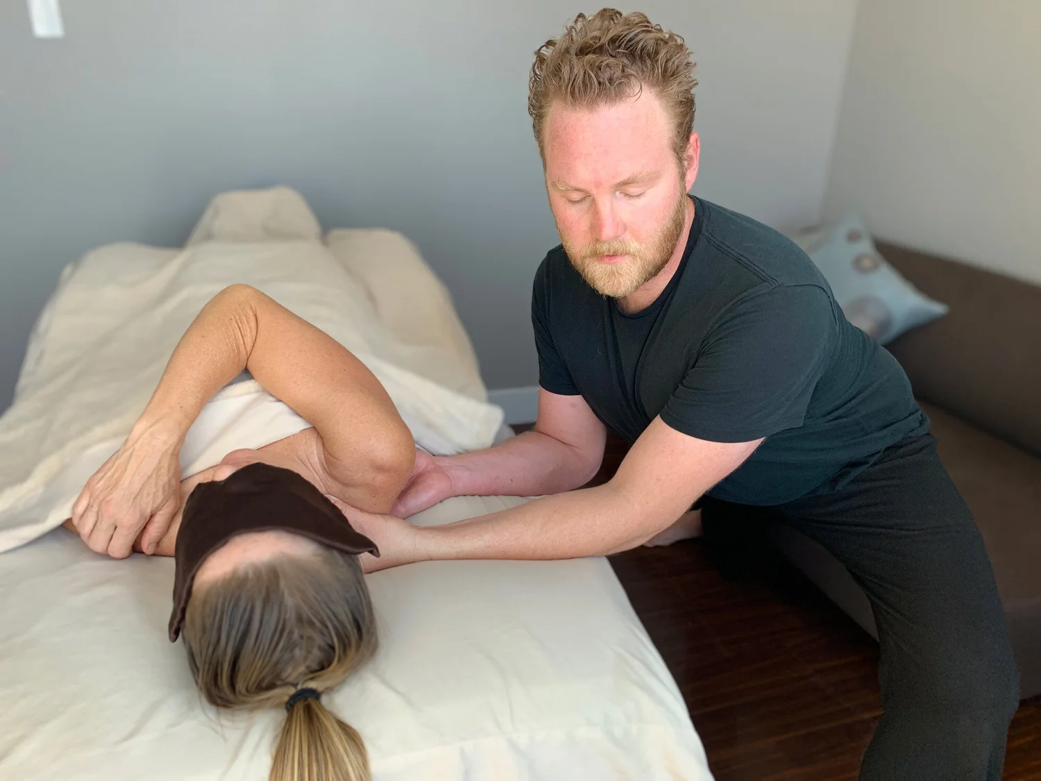 Male massage therapist performing shoulder and upper back massage in professional spa environment.